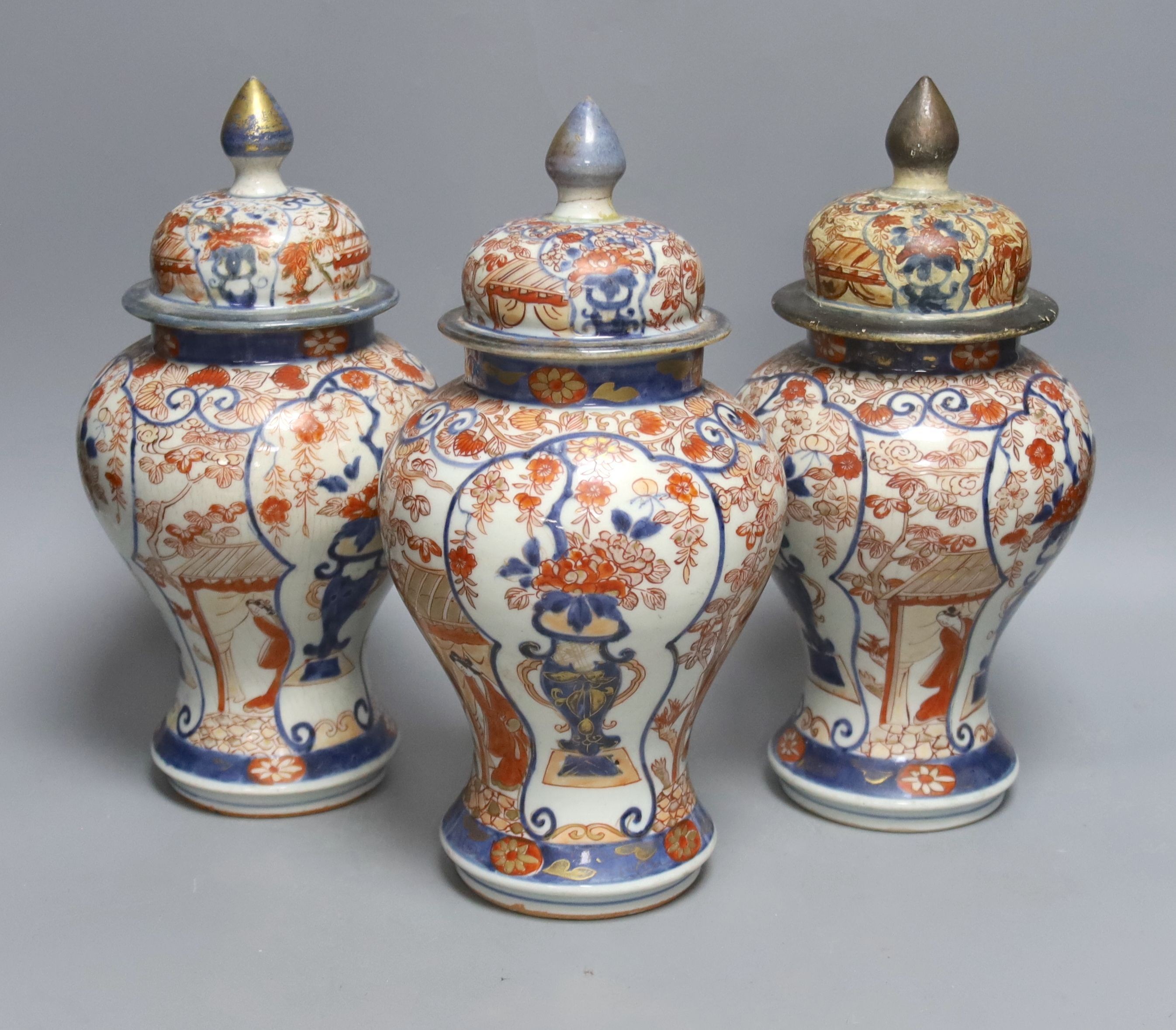 Three 18th century Japanese Arita baluster vases and covers decorated with flowers in urns (damage to covers) 29cm